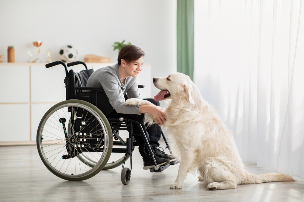 Happy impaired teenager playing with his dog at home highlighting mental health healing trauma and stress relief benefits from animal human friendship